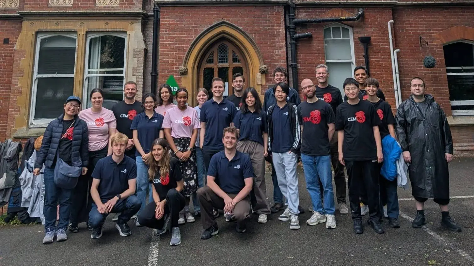 The members of CEMRG standing together outside a red-brick building